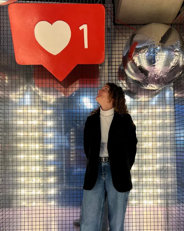 Erica in blazer guarda in su un'insegna gigante con un cuore e il numero 1